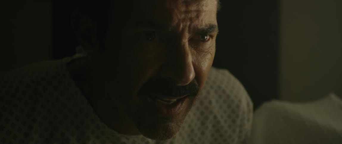 Man with aggressive expression talking in a dark room