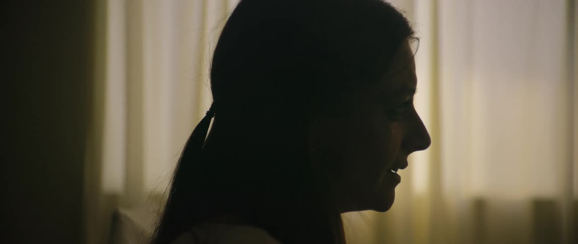 Woman cries while holding a conversation in a curtained room