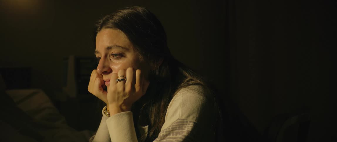 A woman sits with her chin in her hands
