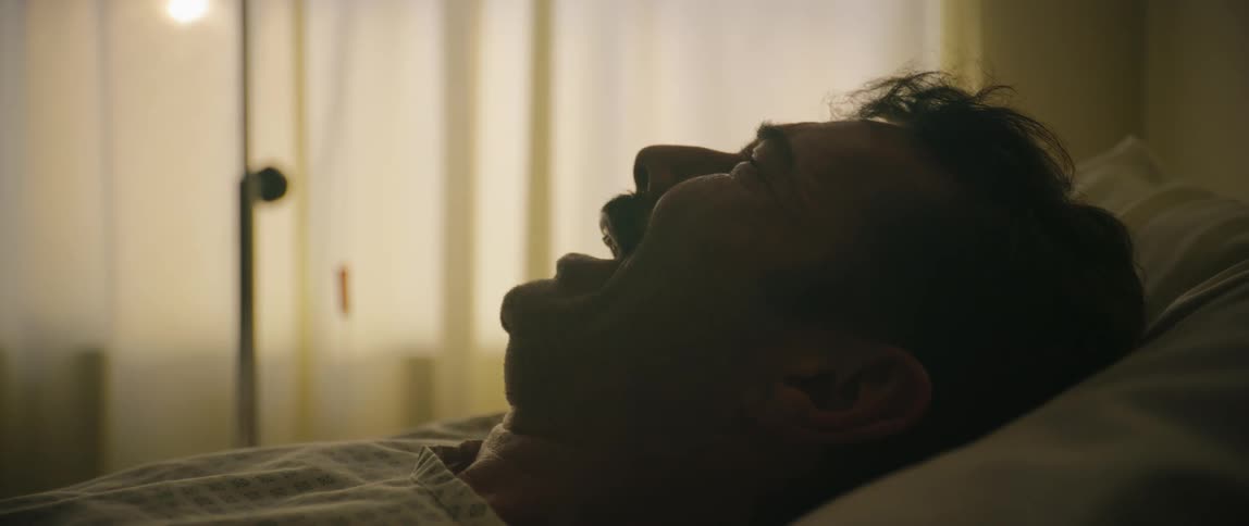A man lying in a hospital bed crying
