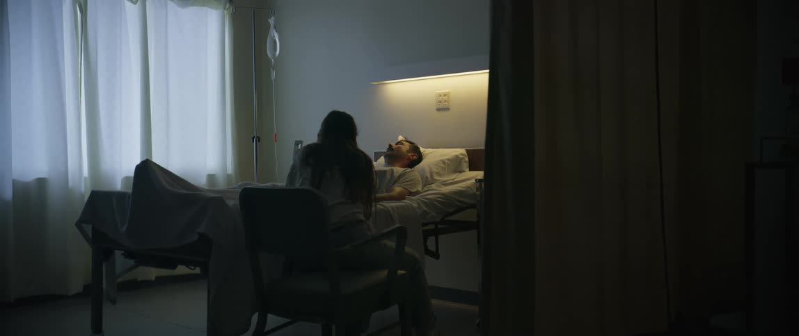 Woman sitting in a chair in a hospital room with a sleeping man