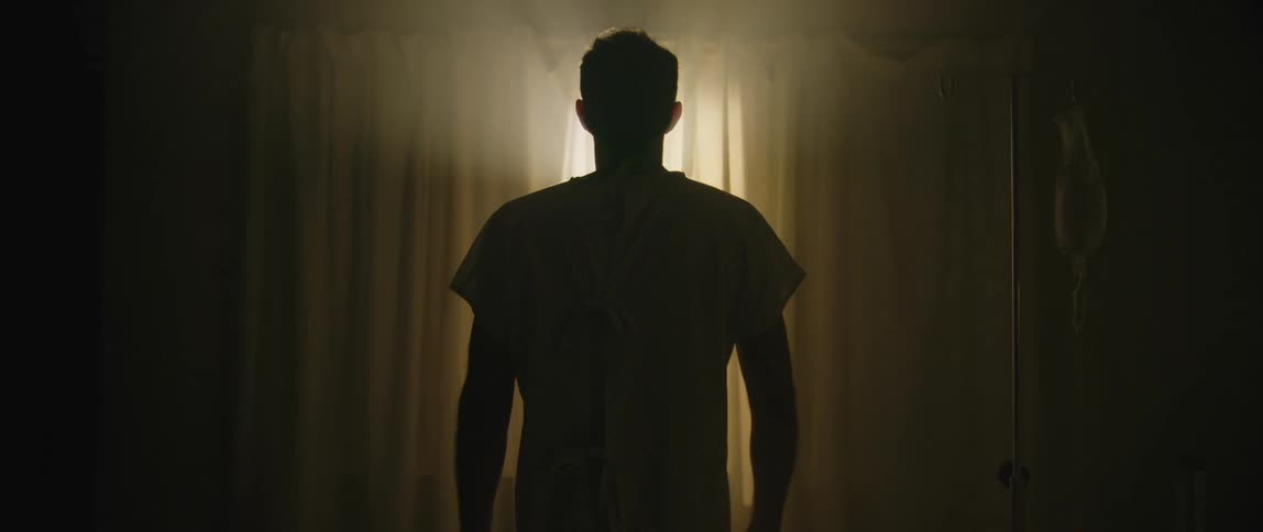 The silhouette of a person standing looking out a window that is illuminating the room with natural light