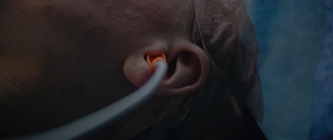 A person inserts a plugged tube into a patients ear