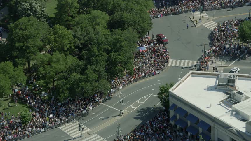 Crowds gather and line the streets in an urban area