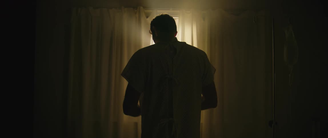 A man stands in front of a window