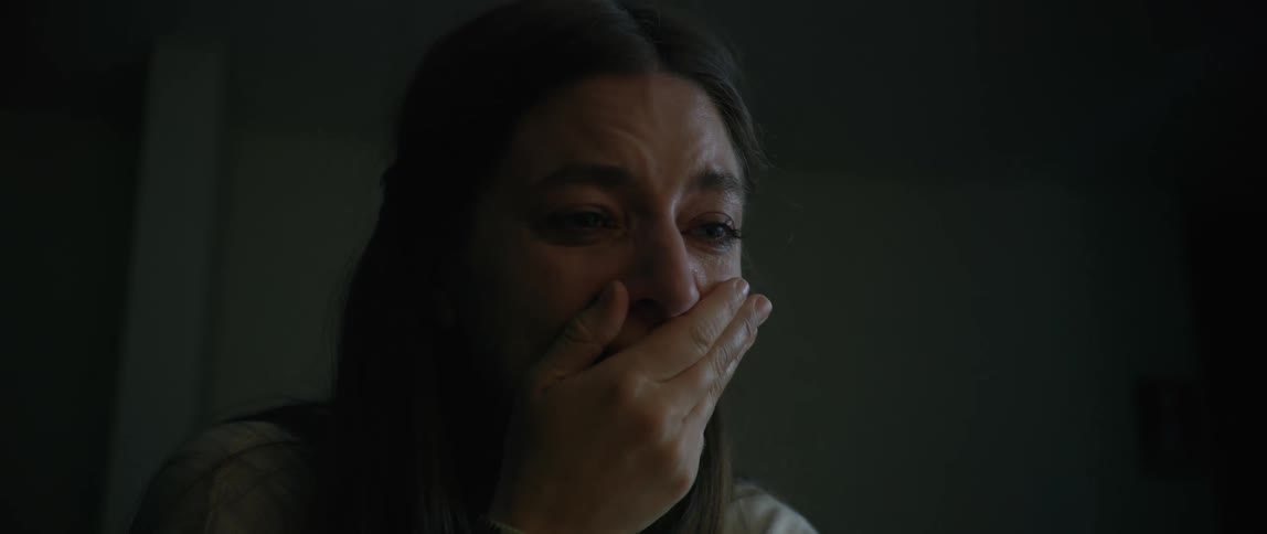 A lady crying in a dark room at night