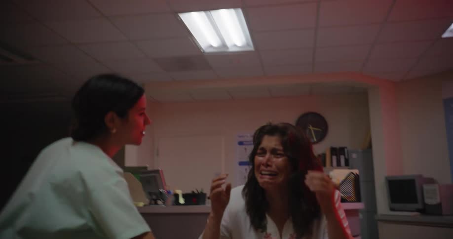 Nurses moving a sick person on a stretcher while a woman nearby cries in despair