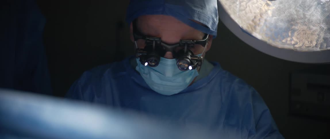 A surgeon looks down at something