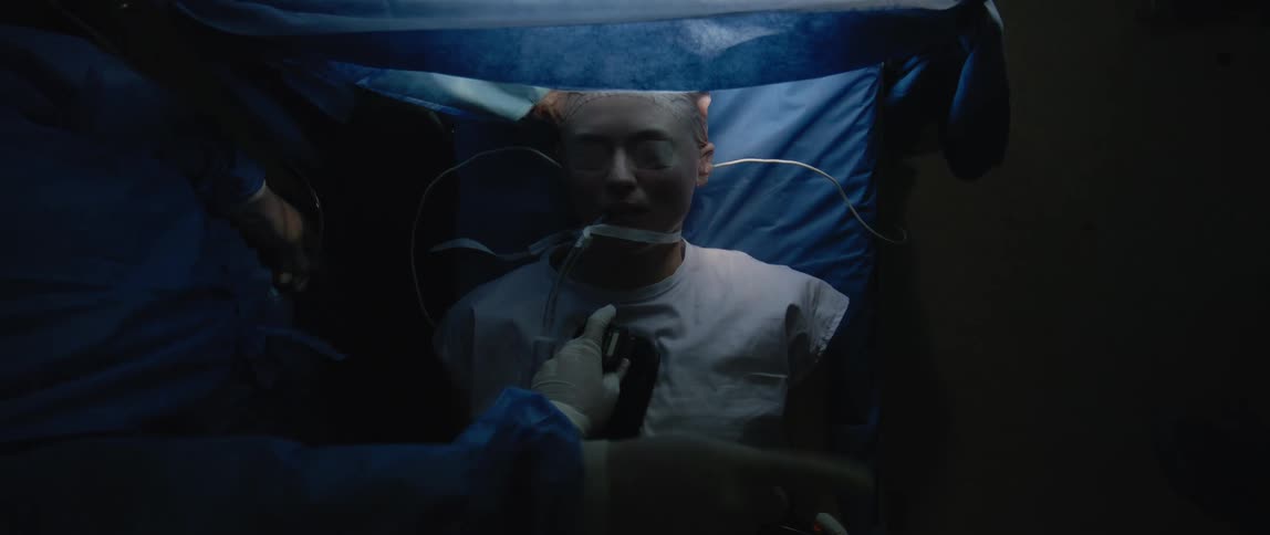 A person connected to a ventilator lies under sterile blue sheets as defibrillation paddles are applied highlighting a critical and potentially life saving medical event