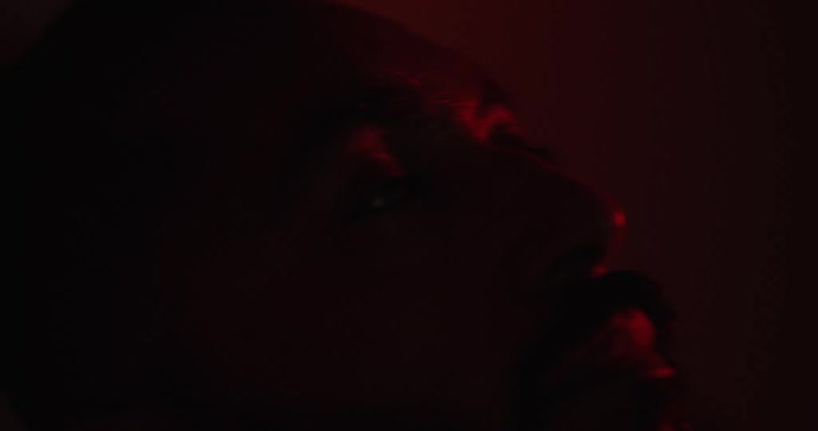 A man wakes up as red light flashes on his face