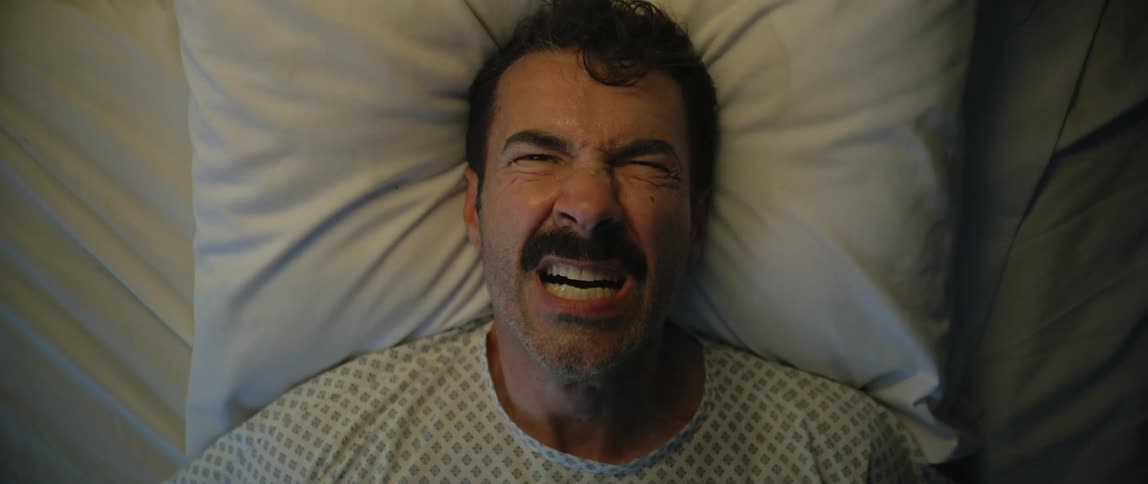 Man lying on a bed screaming in pain