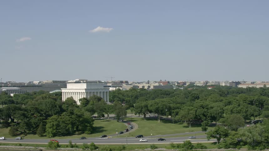White building with pillars surrounded by trees in city