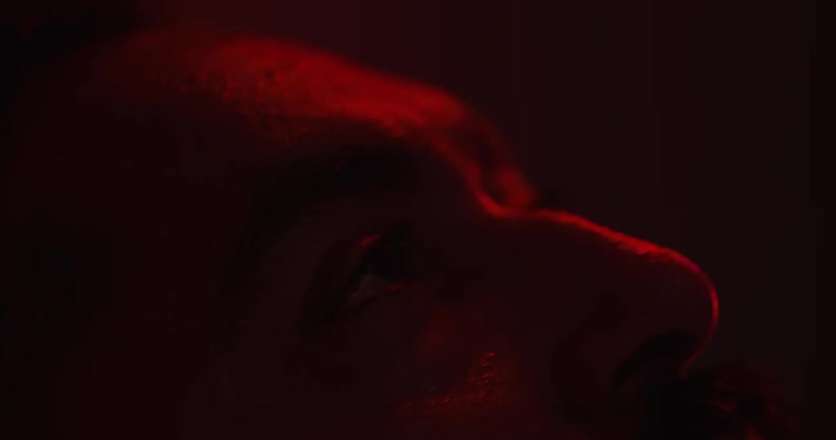 A man is sweating as red light flashes on his face