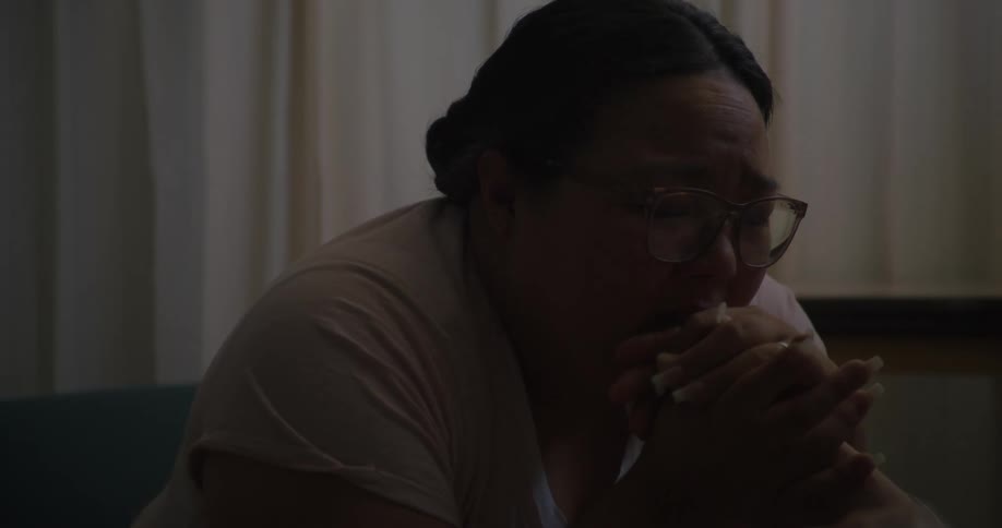 A woman is crying as she holds the hand of a hospital patient