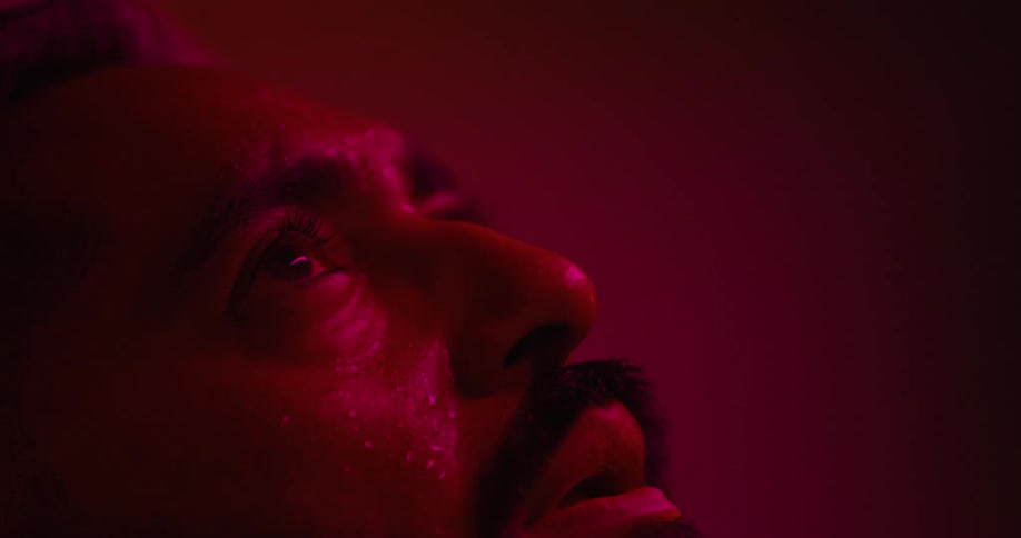 A sick man sweats as a red light shines on his face
