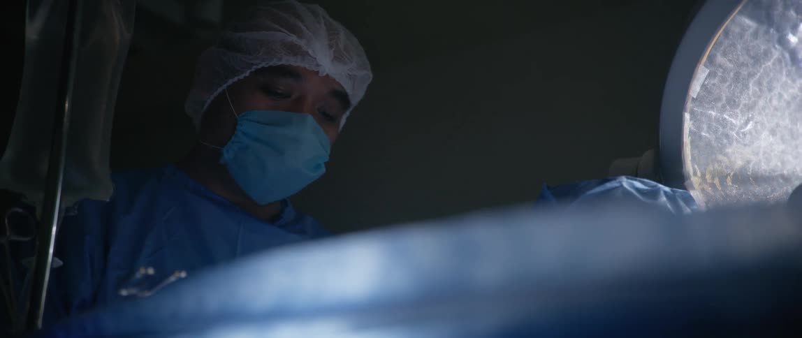 Two draped surgeons perform a surgery in an operating theater