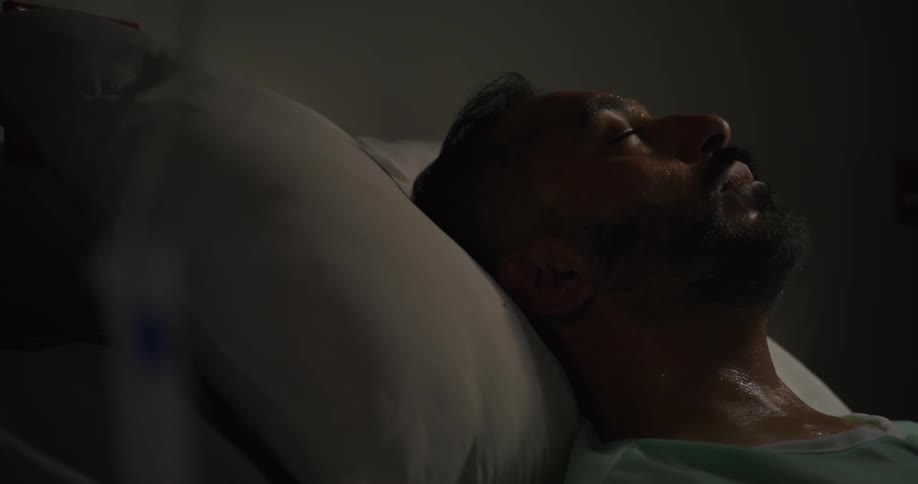A sick patient is sweating as he sleeps in the hospital