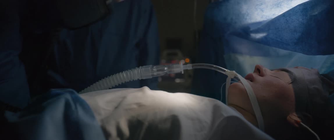 Healthcare worker holds defibrillator paddles over the chest of an intubated patient during a resuscitation procedure
