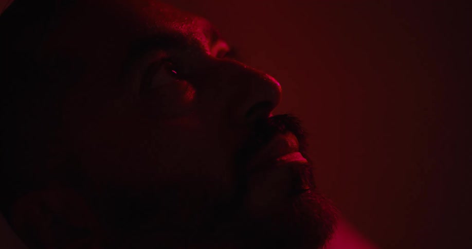 Man moves his head back and forth while lying in a room lit by red lighting