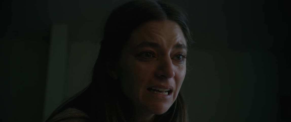 A woman covers her mouth and then tries to speak as she cries