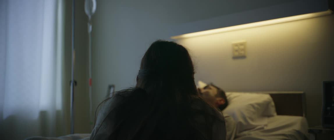 A woman looks at a patient laying in a hospital bed