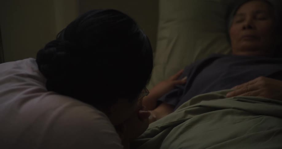 A footage of an emotional woman holding an elderly woman on a sick bed