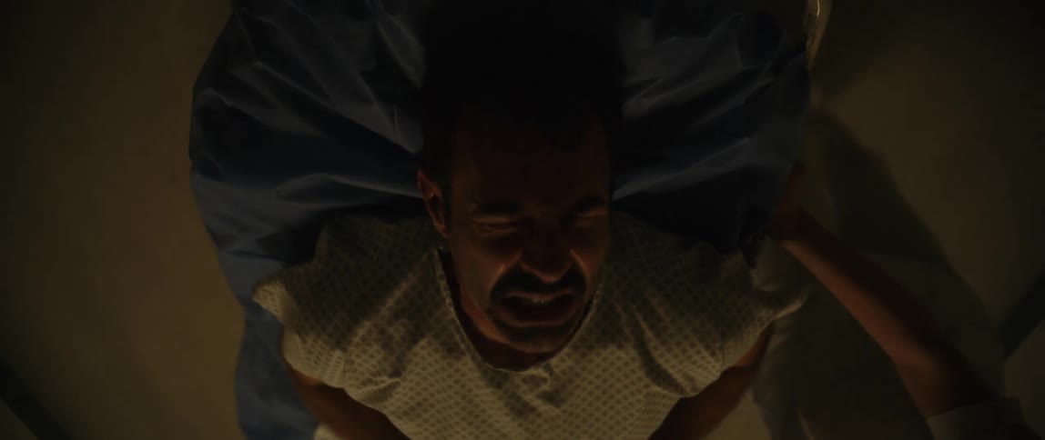 A man in anguish is being carried on a stretcher by nurses in the emergency room