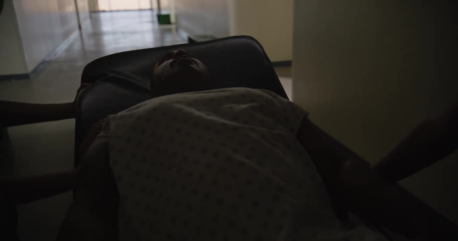 A sick patient is pushed down the hall of the hospital on a gurney