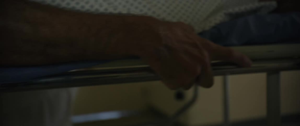 Medical professional gripping side of hospital bed rushing patient to emergency room