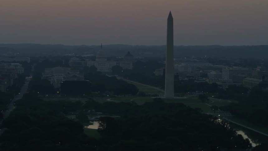 A tall pillar sits in the city at dawn