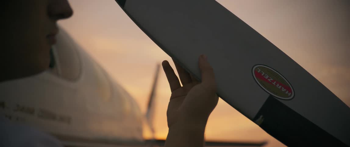 A pilot is examining the propeller on the plane