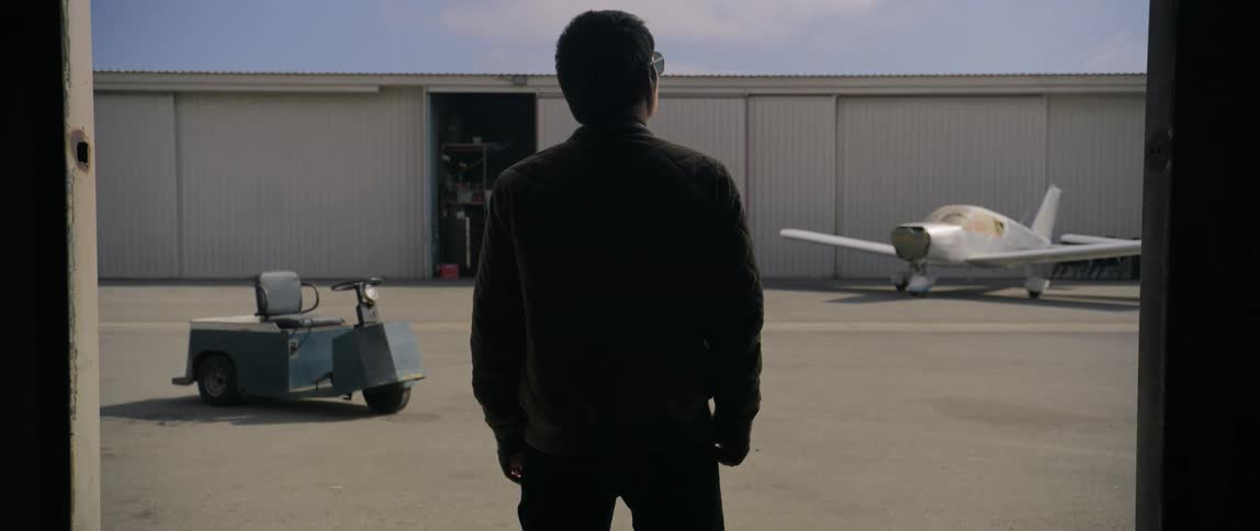 A man opens the hangar doors on the airfield