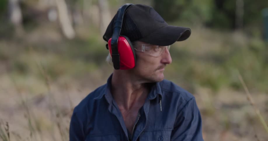 A man stops using a chainsaw and talks with someone