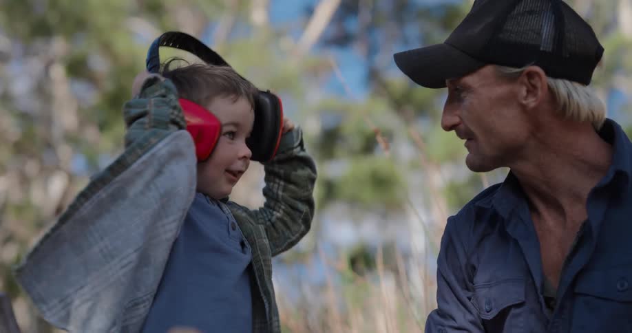 A happy father and son smiling and playing together outdoors