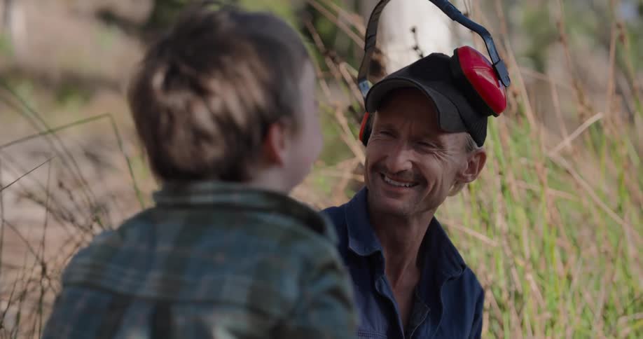 A father and son laugh by the tall grass