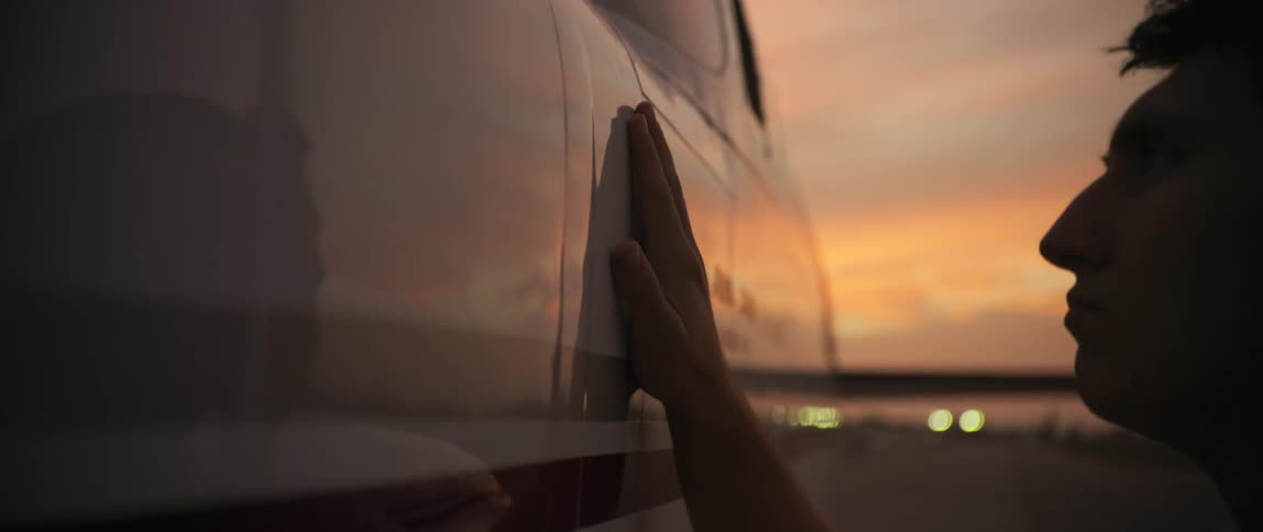 A man touches and rubs the body of an aircraft outside at dusk