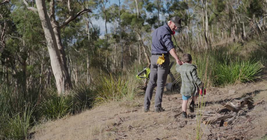 Father holding hands with young son walking through a wooded trail nature area