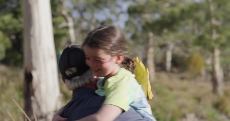 A girl runs up to a man in a forest area and hugs him at daytime