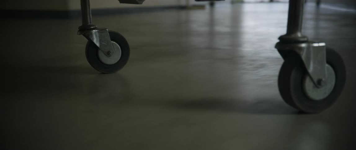 Closeup of the wheels of a stretcher moving down a hospital corridor