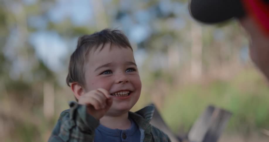 A boy laughs and his father rubs his head