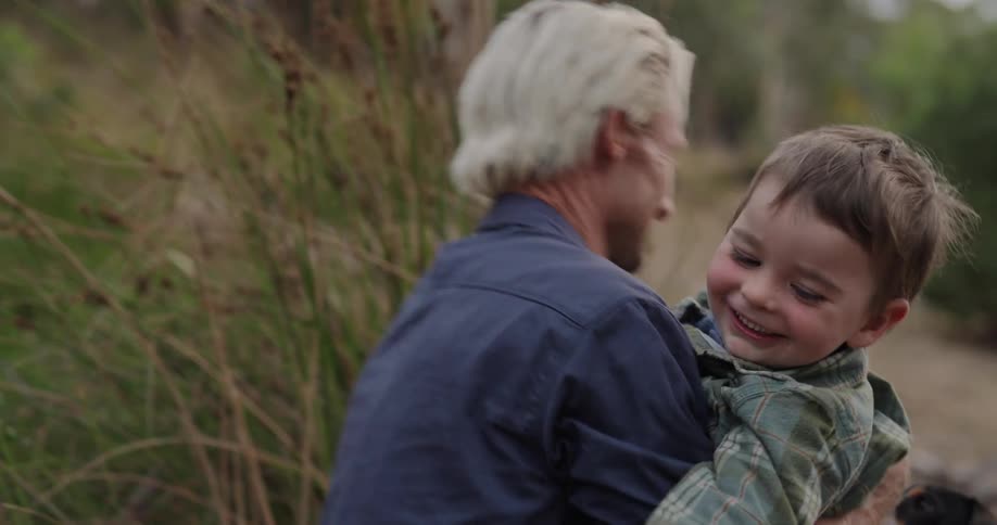 A little boy runs up and hugs his father