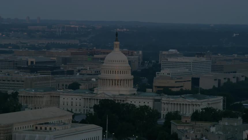 The u.s. capitol building stands amidst other buildings at dusk or dawn