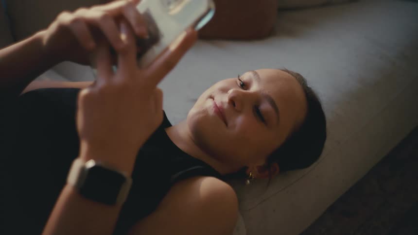 A woman texts on her phone and puts it to the side