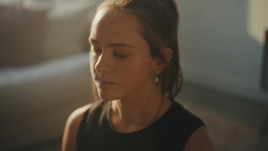 A woman breaths deeply and begins meditating