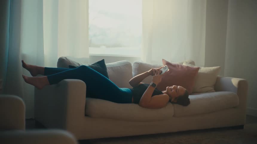 A woman is laughing while using her cell phone