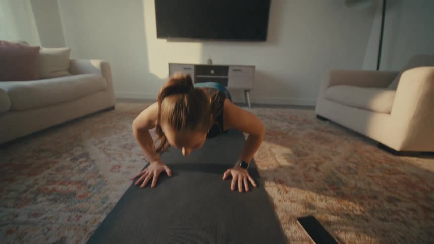 Woman doing pushups and jumping on living room rug