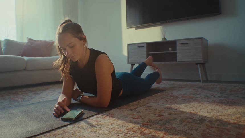 A woman uses her phone then does yoga
