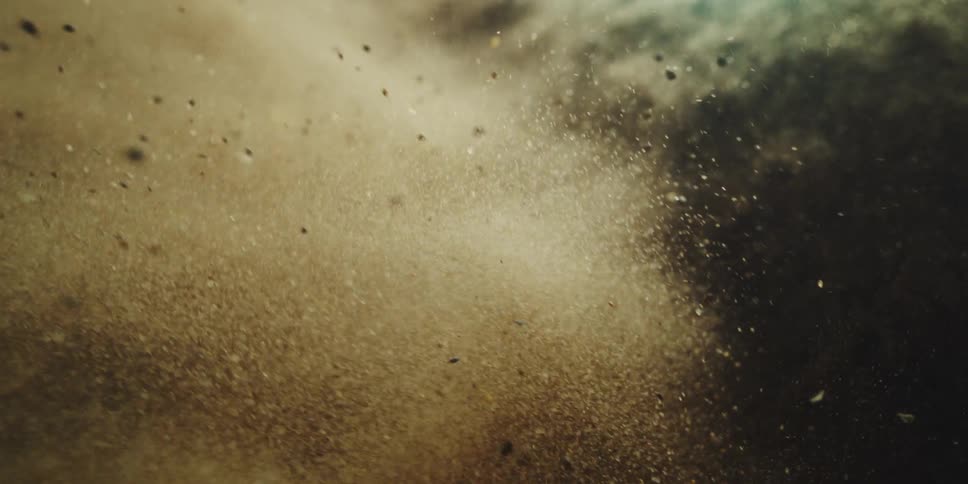 Sand and tiny rocks crash into the ocean from somewhere above