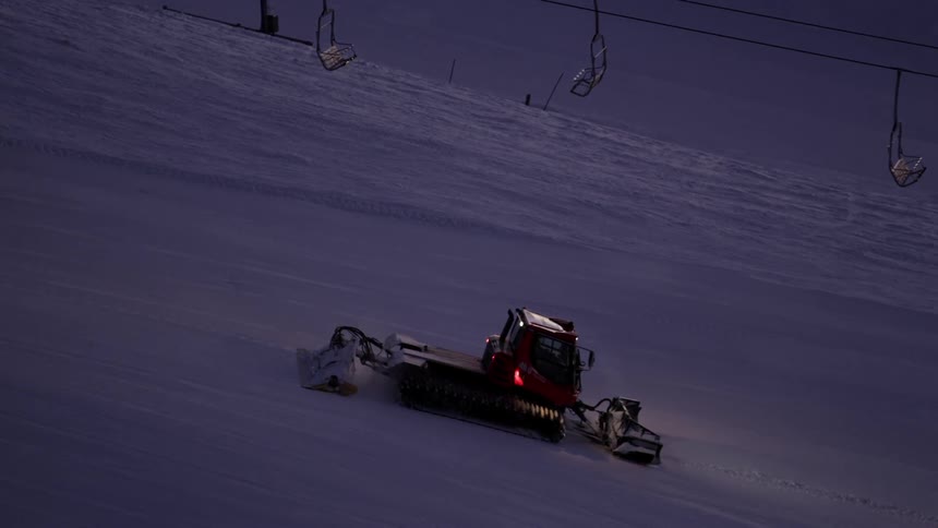Tractor going down a hill, smoothing out the snow at a ski resort