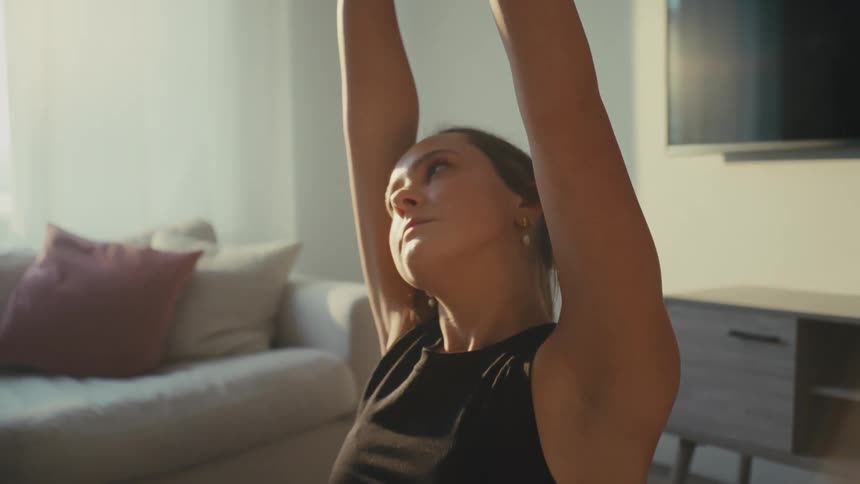 Woman stretches while exercising in her living room during the daytime
